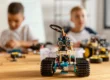 Robot de juguete construido con piezas de bloques, motores y sensores electrónicos en un taller de robótica educativa.