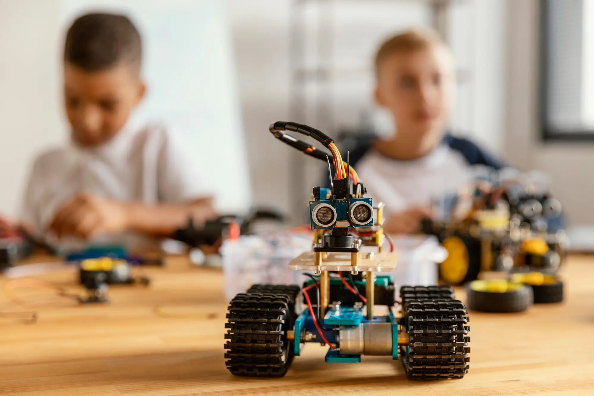 Robot de juguete construido con piezas de bloques, motores y sensores electrónicos en un taller de robótica educativa.